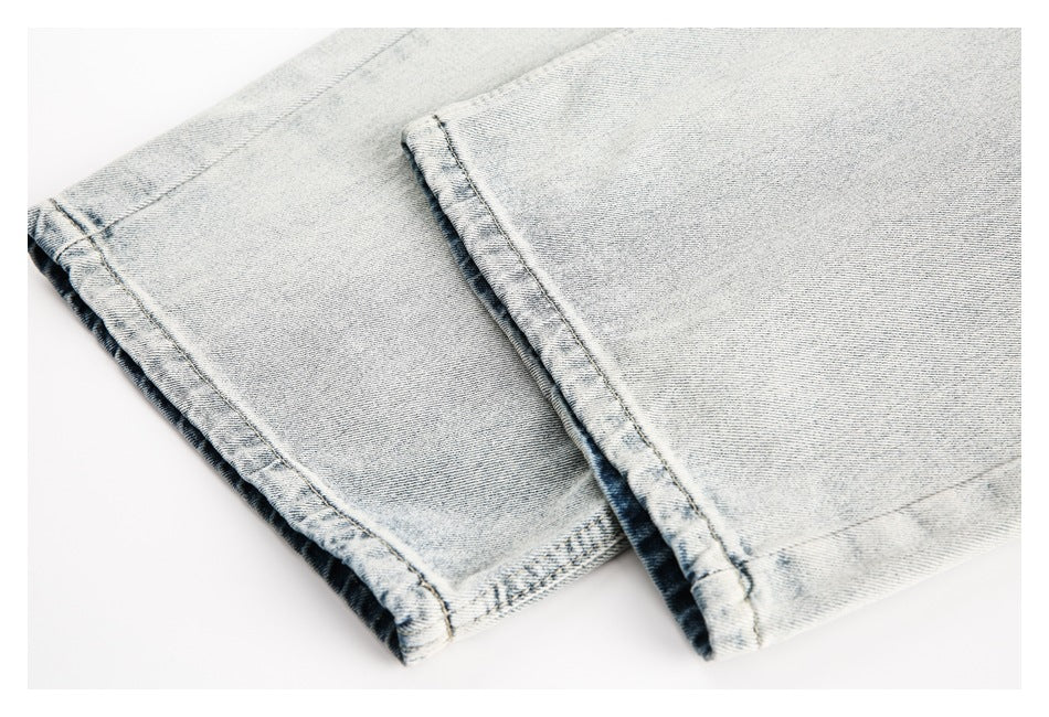 Close-up of light-wash jean leg hems with visible seams and folded edges.