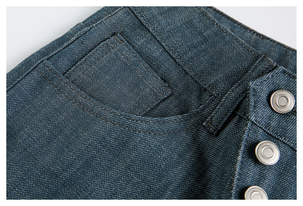 Close-up of a small front coin pocket, belt loop, and metal buttons on dark blue pants.