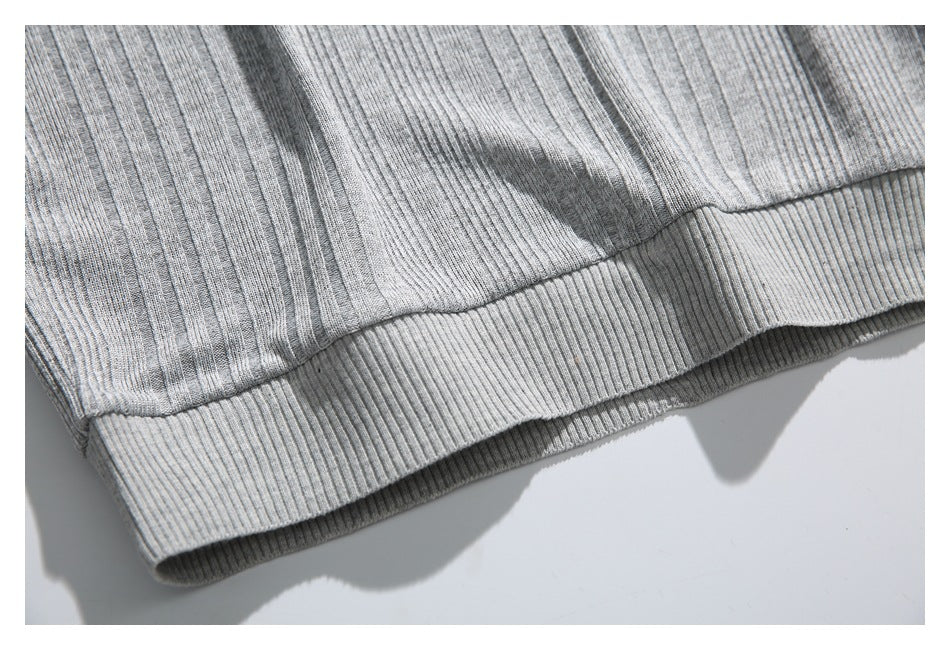 Close-up of the gray polo shirt's ribbed bottom hem and knit texture.