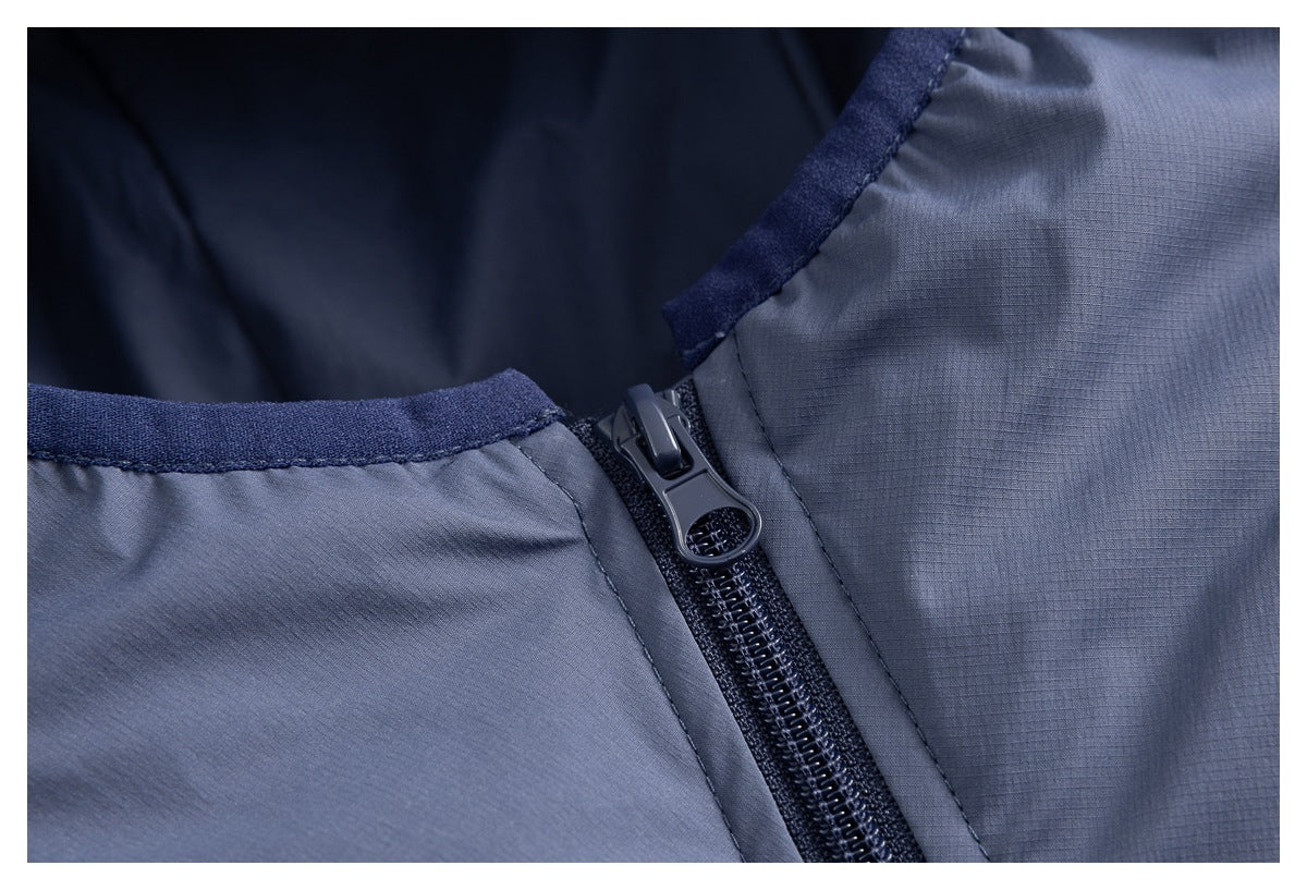 Close-up of the jacket's front zipper, pull, hood-edge trim, and slate-blue fabric.