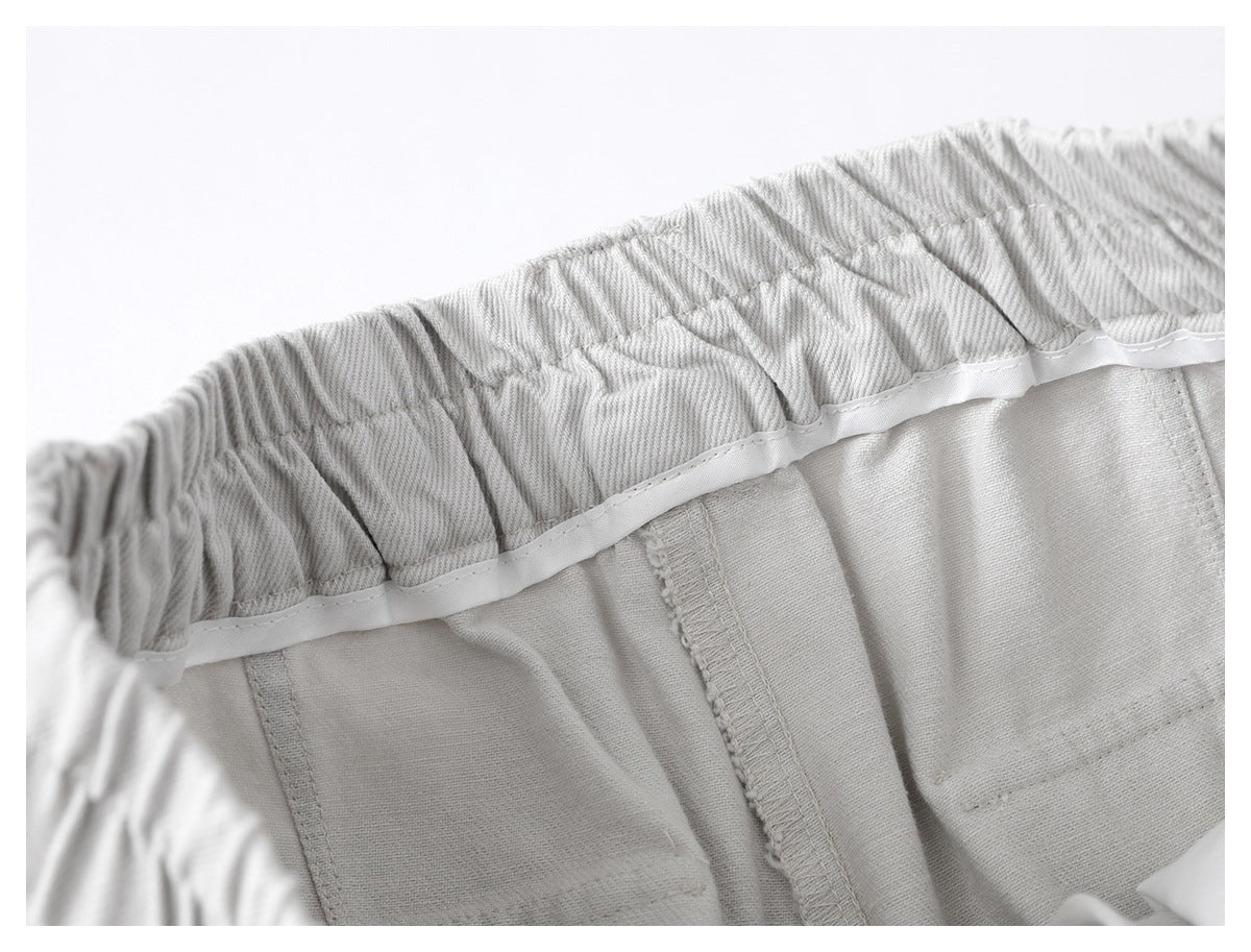 Inside close-up of light gray trousers showing elastic waistband construction and stitched seams.