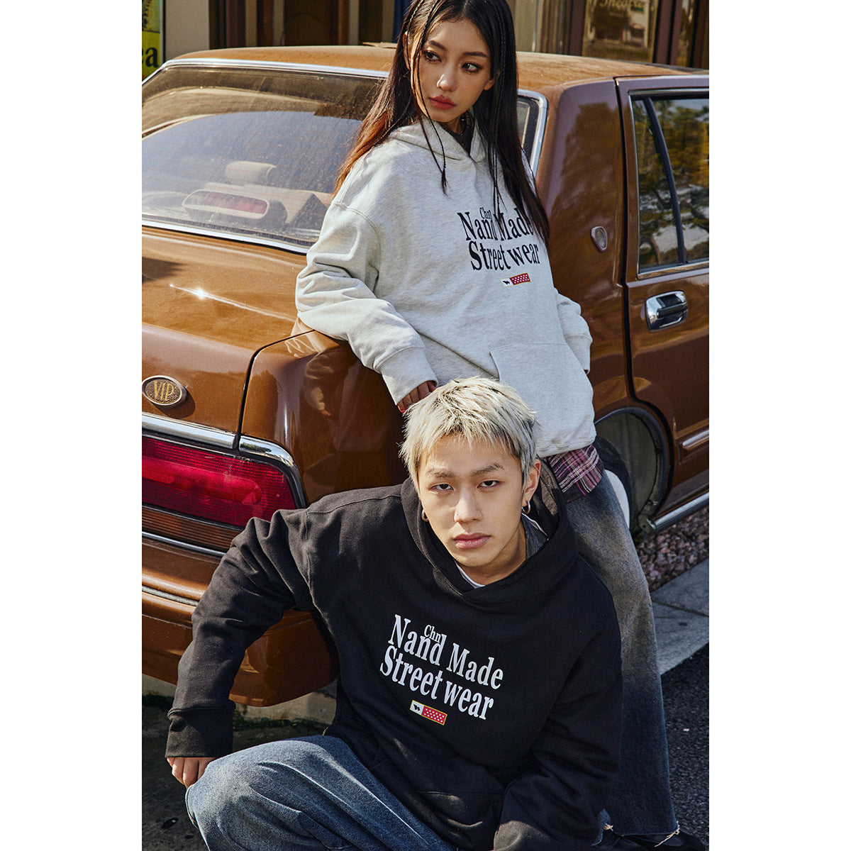 Two models show the hoodie in light gray and black; both have a front graphic, kangaroo pocket, and drawstring hood.