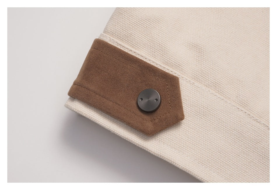 Close-up of a brown cuff tab with a dark button on a cream textured coat.