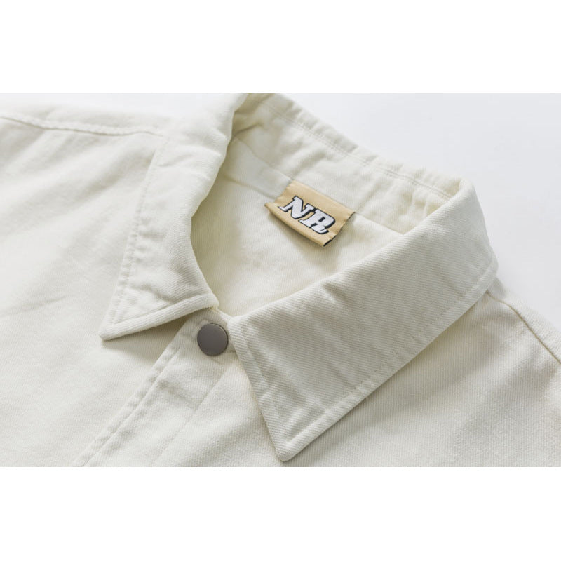 Close-up of an off-white shirt-jacket collar, gray snap button, and tan neck label.