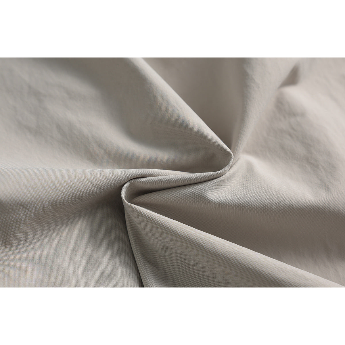 Close-up of the light beige trouser fabric draped to show its surface and folds.