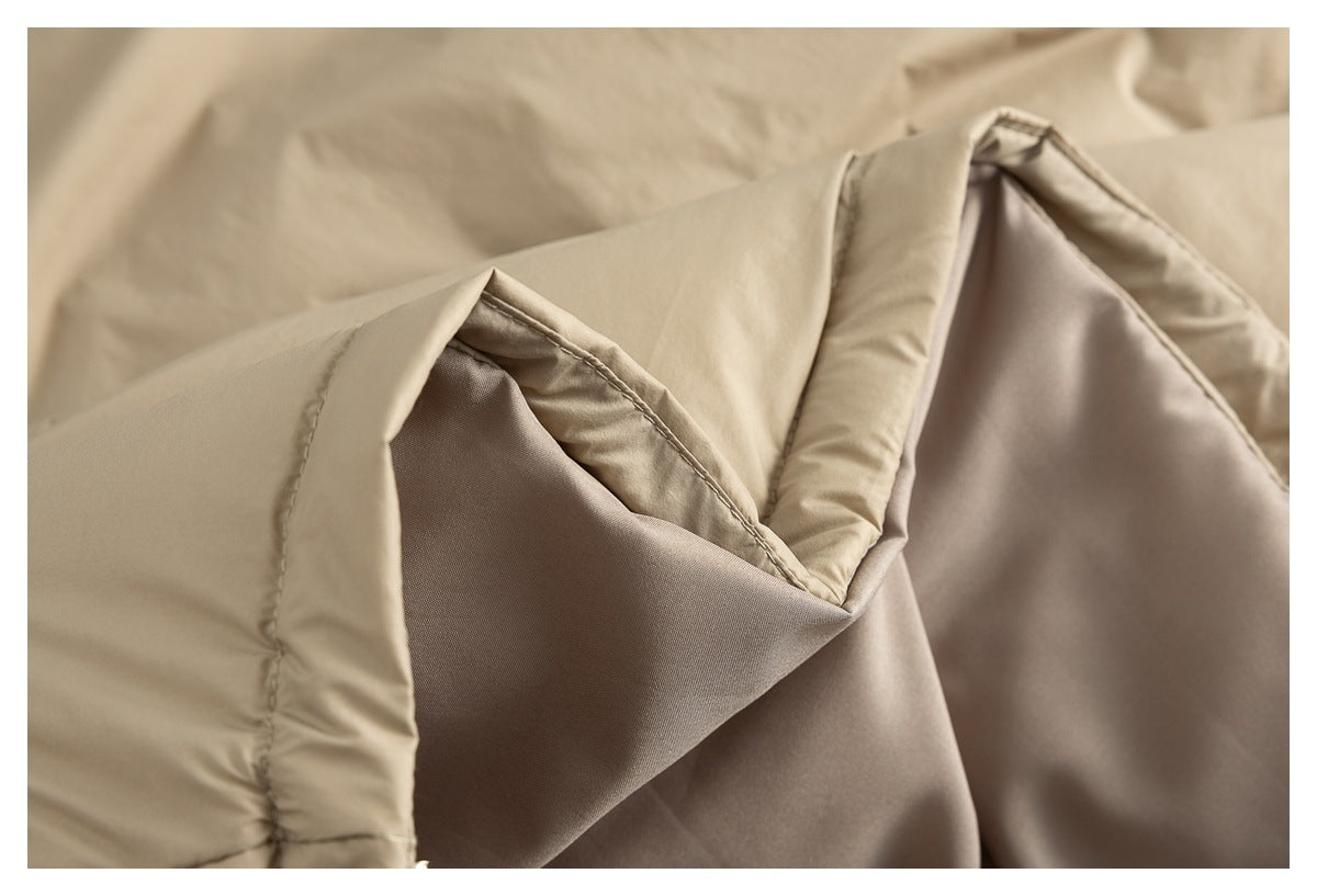 Close-up showing the folded edge and inner lining of a beige quilted comforter.