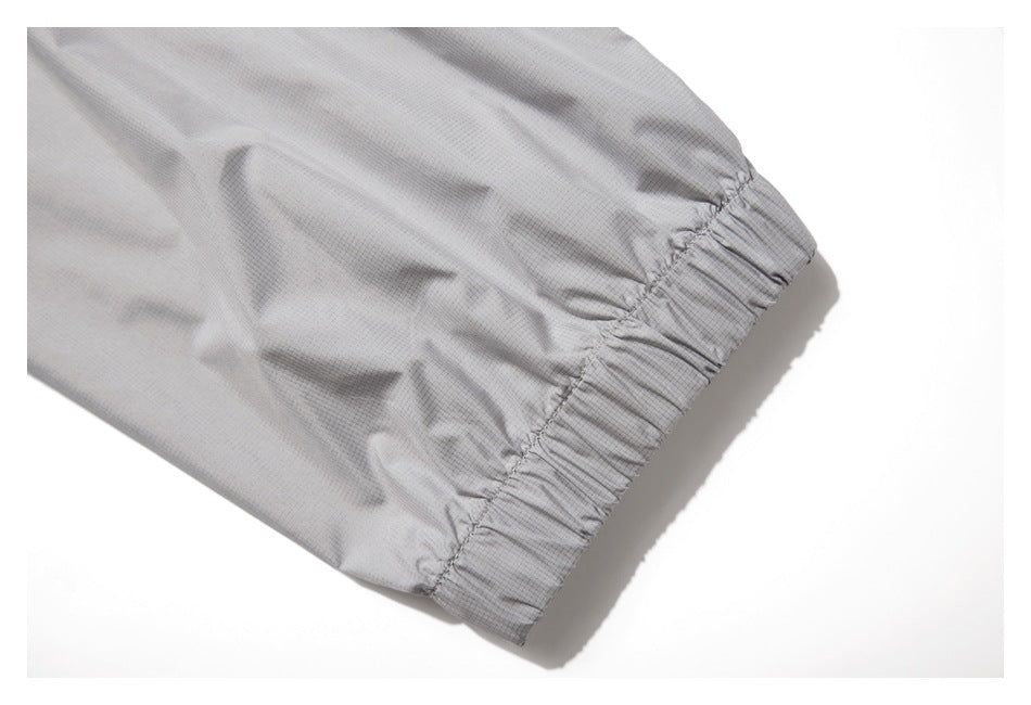 Close-up of light gray fabric with a fine grid texture and a gathered elastic cuff.