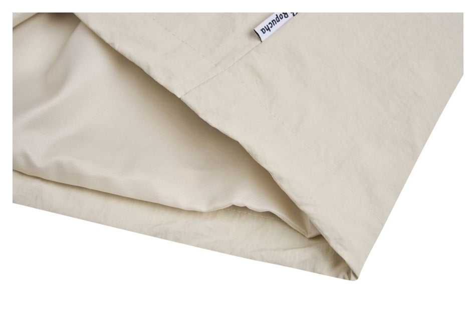 Close-up of the ivory garment hem, showing its lining and a small sewn-in label.