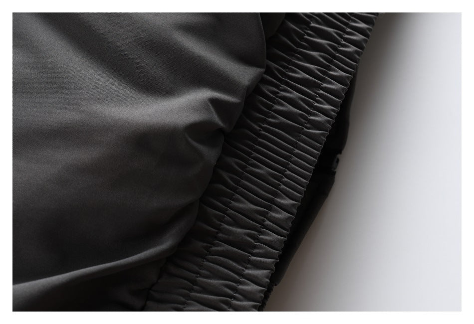 Close-up of black jacket fabric beside a wide gathered elastic band.