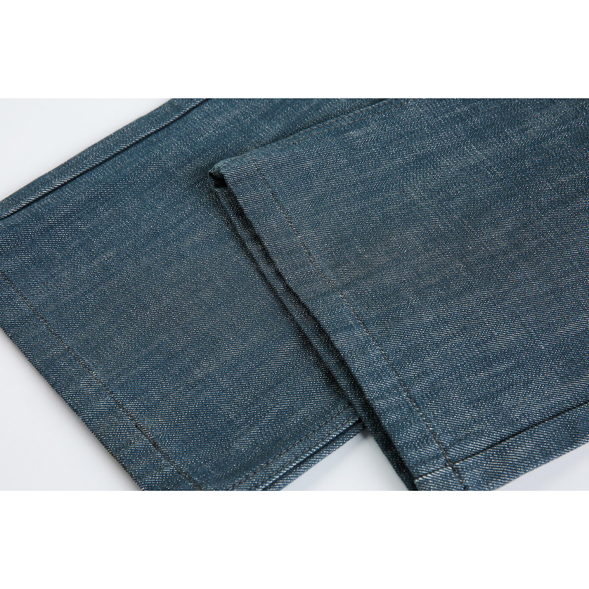 Close-up of blue-gray trouser fabric, a stitched seam and the finished leg hem.