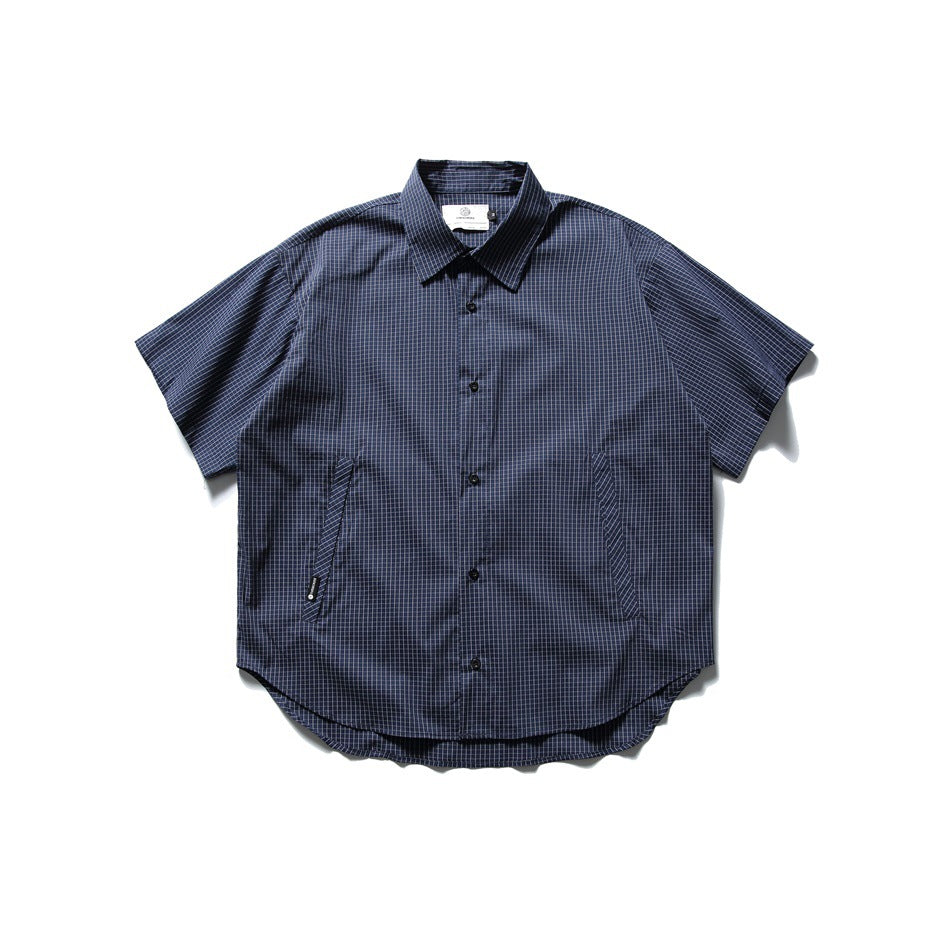 Navy short-sleeve button-up shirt with fine light grid check, slanted side pockets and curved hem, flat lay