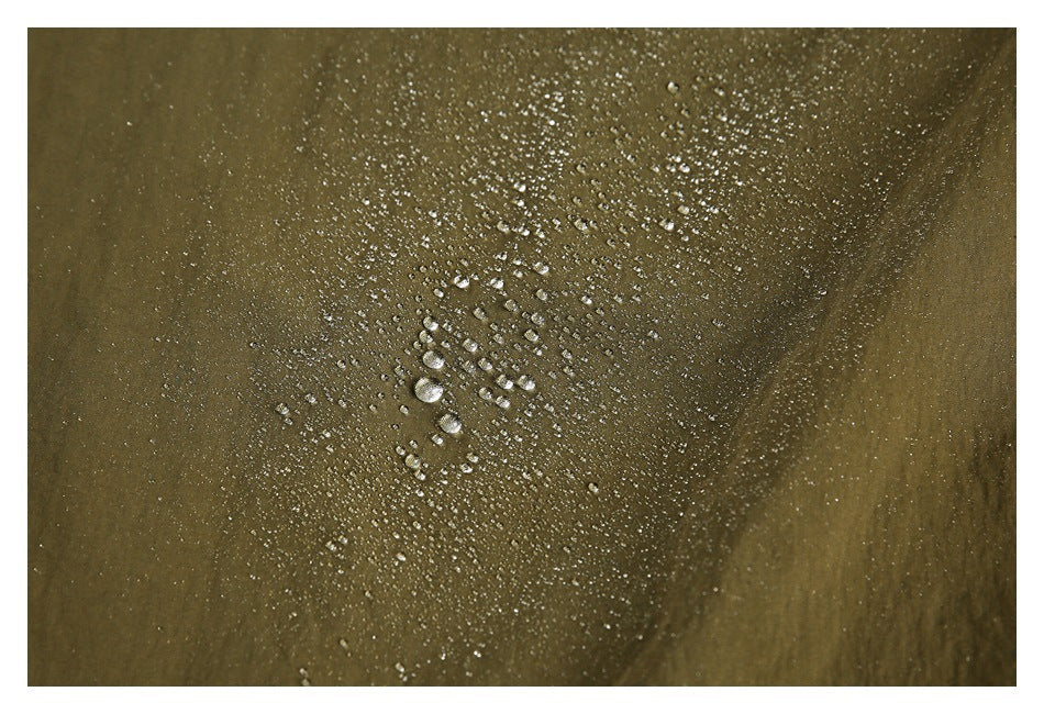 Water droplets bead on the olive garment fabric in a close-up.