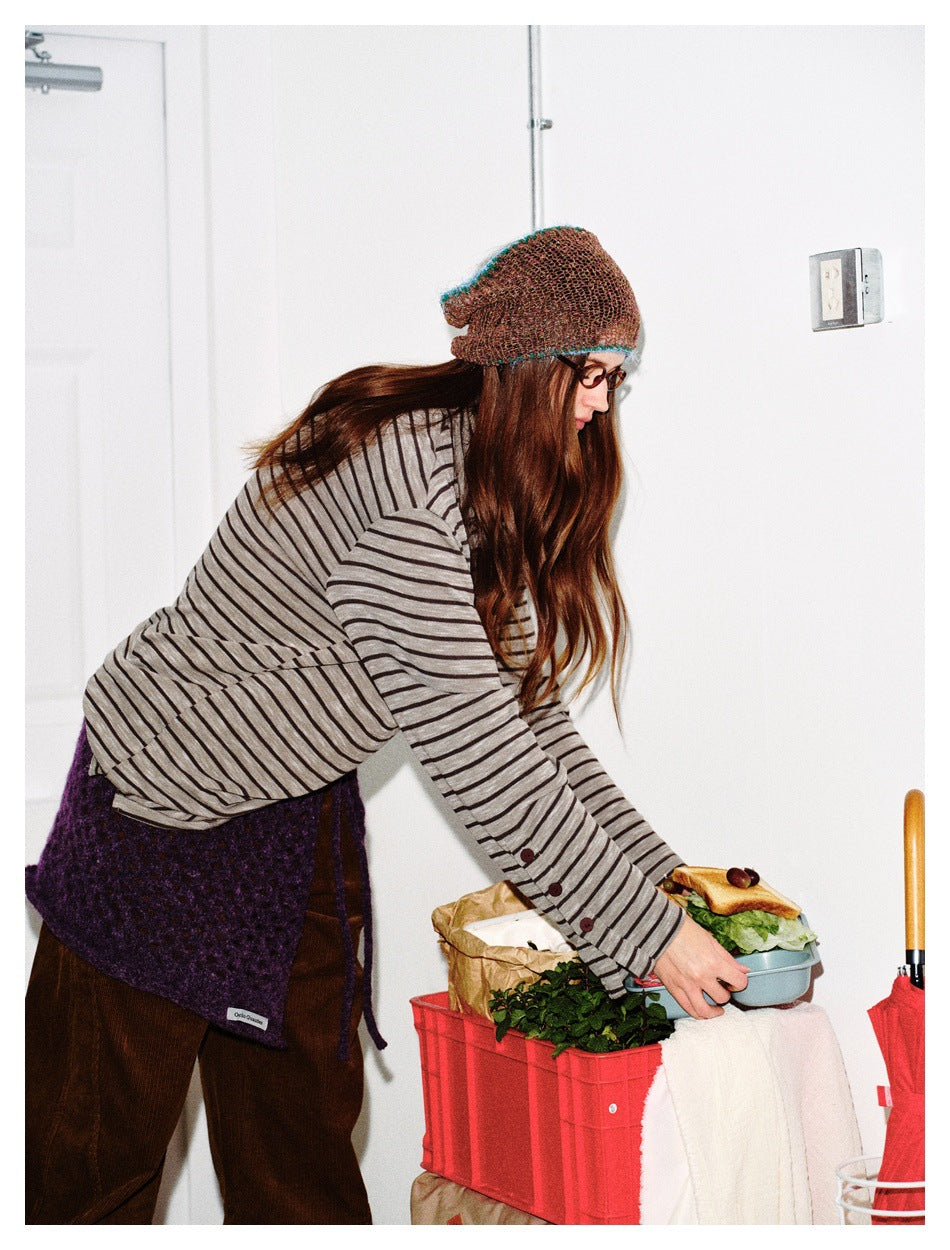 Woman leaning forward in the striped long-sleeve top, showing the cuff buttons on the sleeve