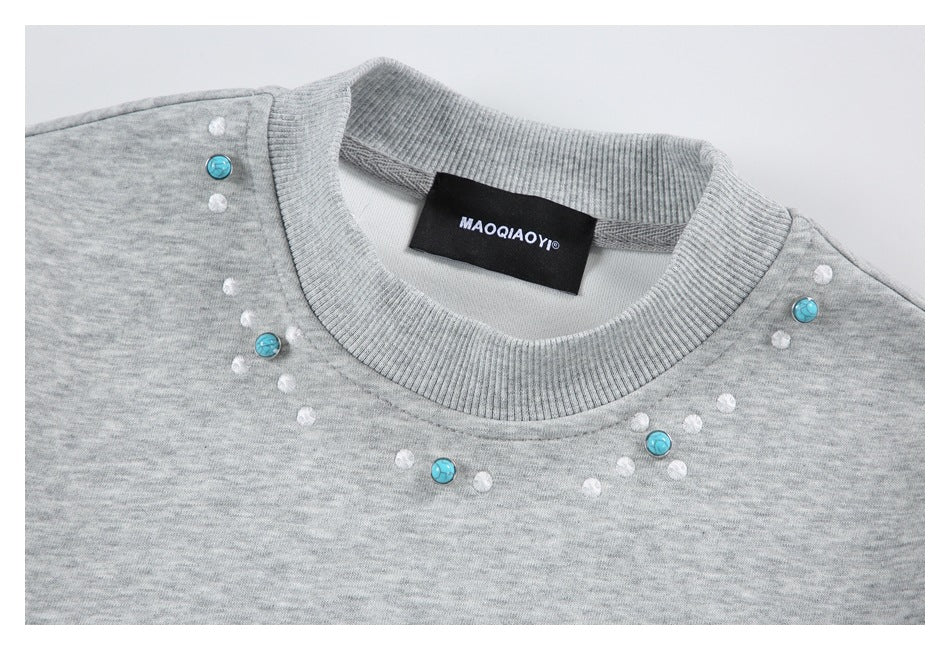 Close-up of a heather gray sweatshirt neckline with white stitched dots, turquoise buttons, and a black sewn-in label.