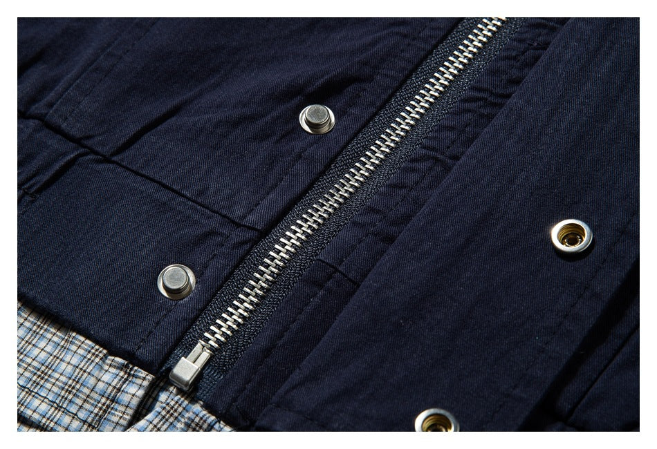 Close-up of a navy garment with a metal zipper, snap fasteners, and plaid lining.