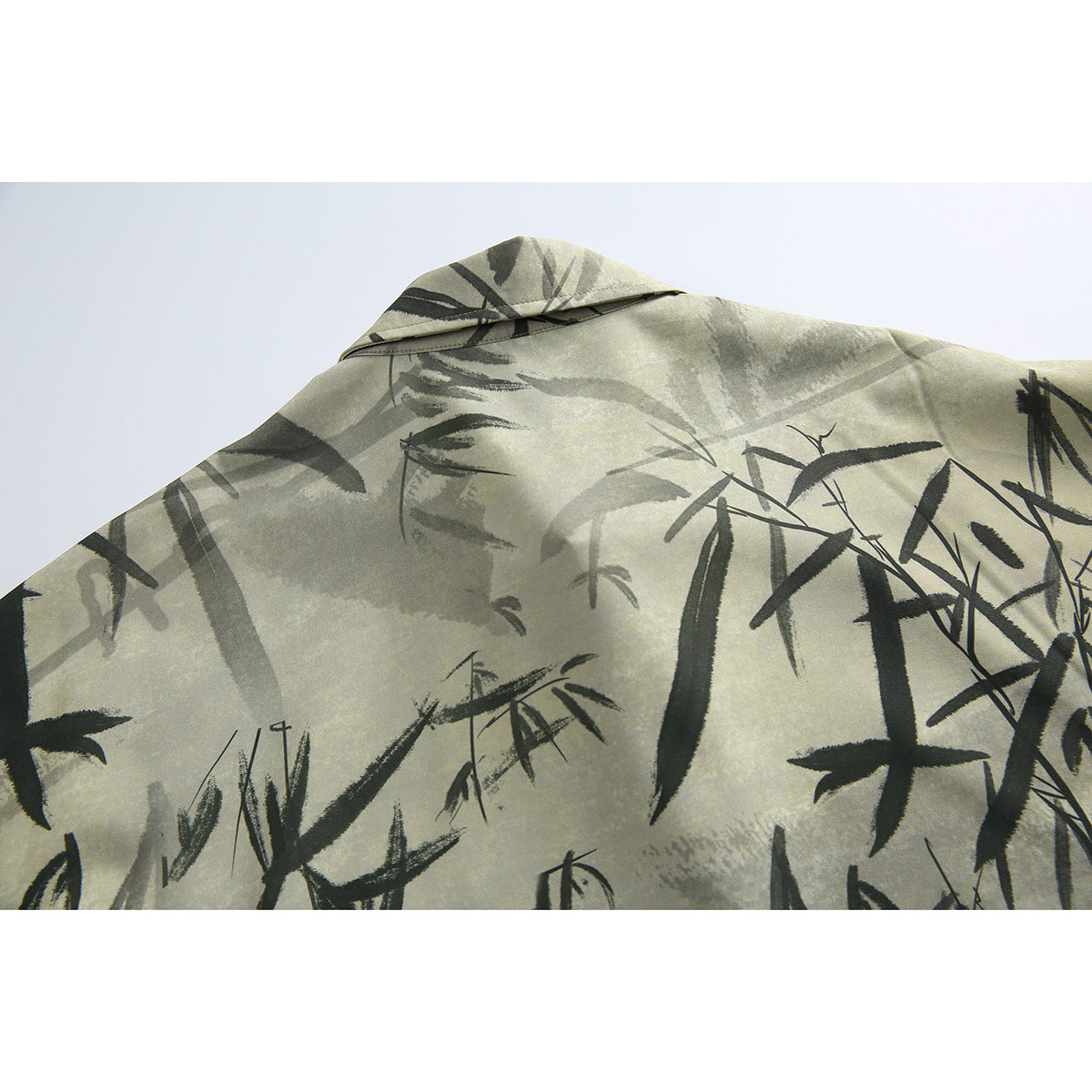 Close-up of the back shoulder and collar of a beige-gray shirt with an all-over dark bamboo brushstroke print.