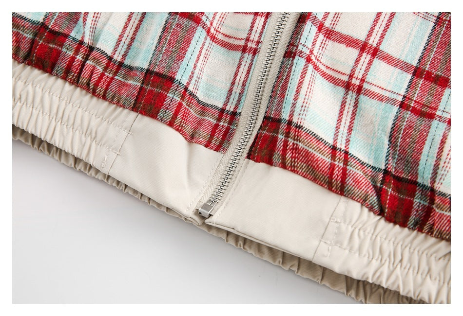 Close-up of a silver zipper and gathered cream waistband trim on red, cream, and pale blue plaid fabric.