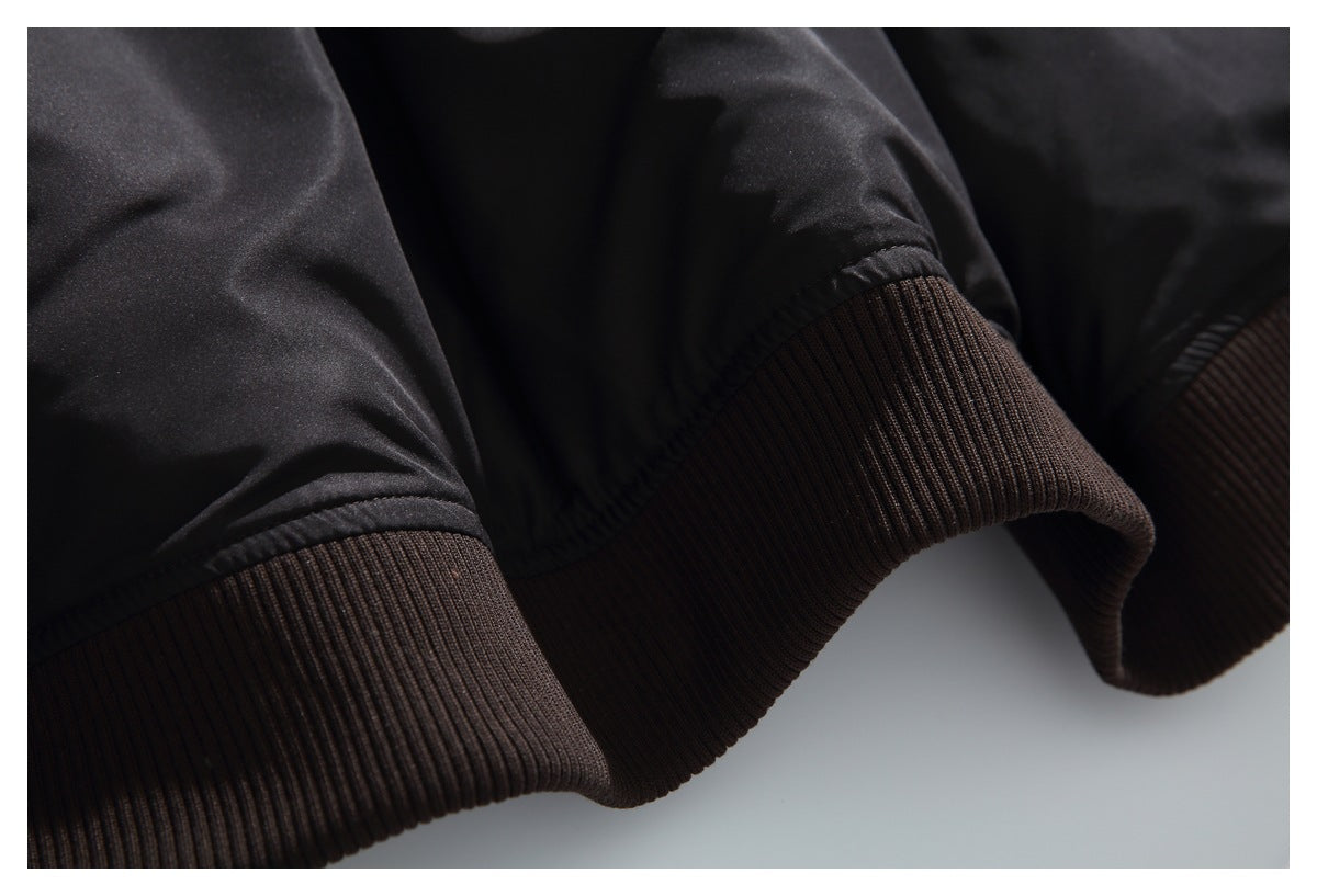 Close-up of a black sleeve ending in a wide dark brown rib-knit cuff.