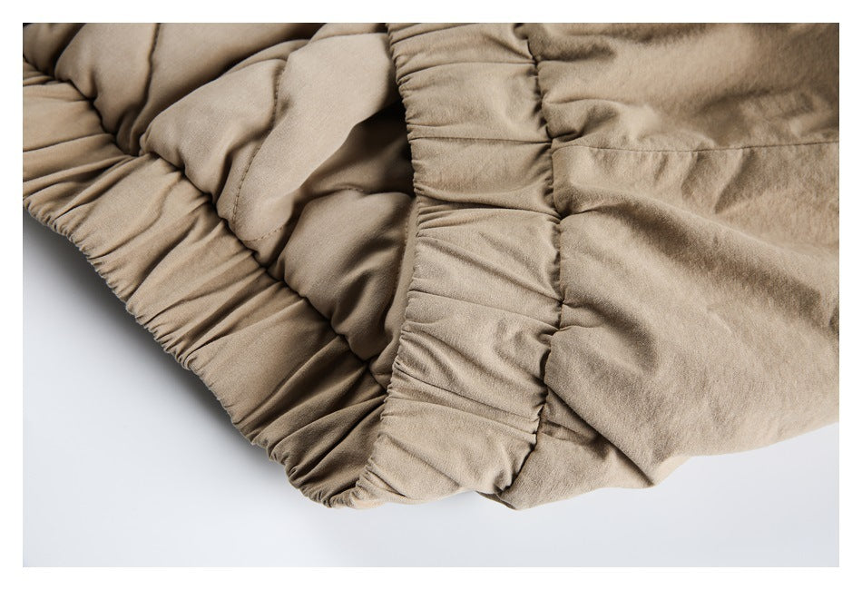 Close-up of beige garment panels with gathered elastic trim and visible stitching.