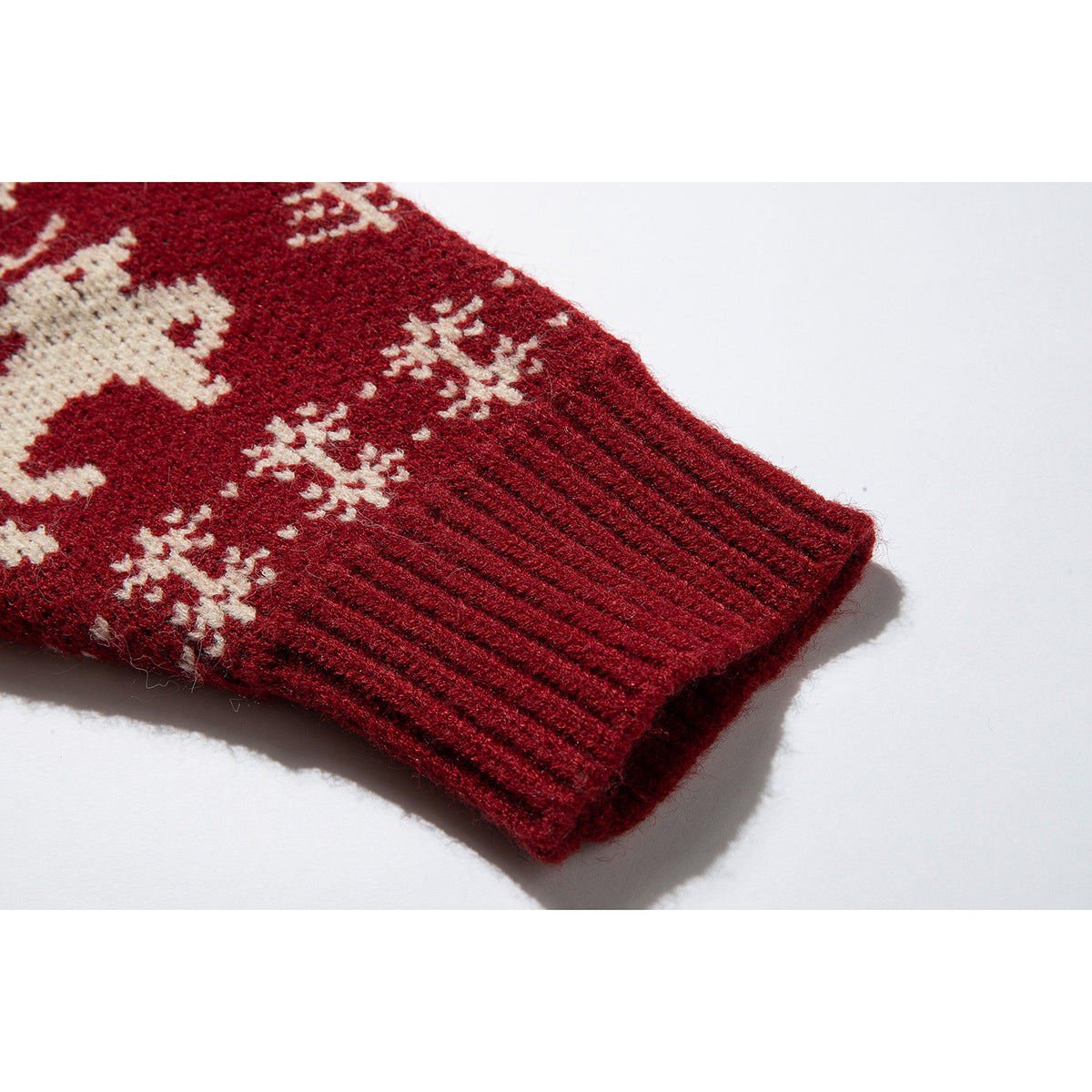 Close-up of a burgundy sweater sleeve with a ribbed cuff and cream snowflake motifs.