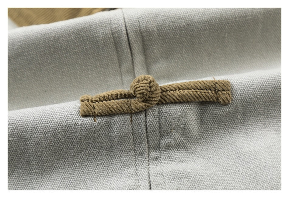 Close-up of a tan corduroy frog closure on the pale gray jacket.