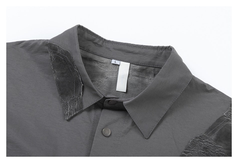 Close-up of the gray shirt's pointed collar, snap-button placket, textured panel, and size label marked L.
