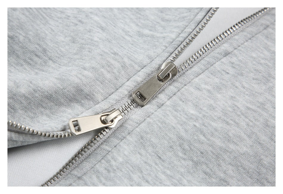 Close-up of the hoodie’s silver double zipper on light gray fabric.