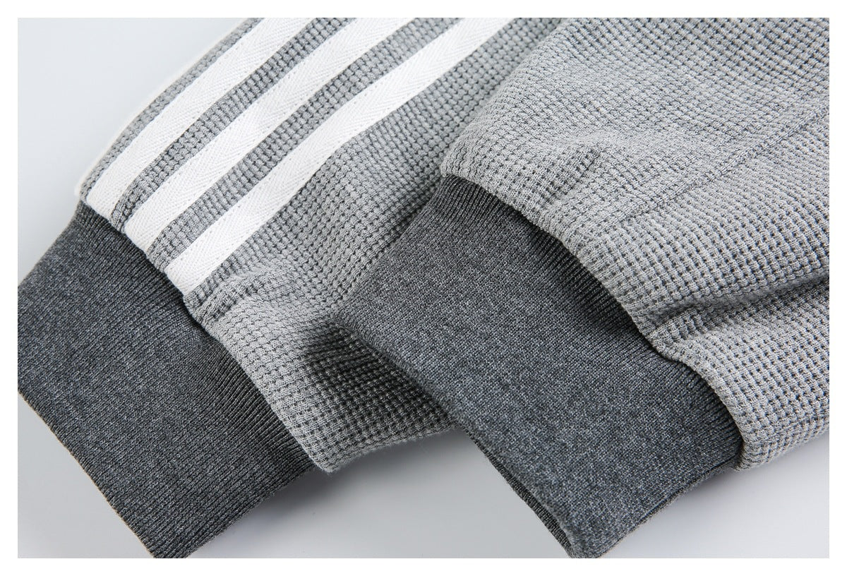Close-up of gray garment cuffs with dark charcoal ribbed bands and white stripes.