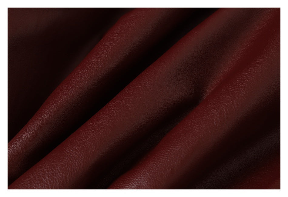 Extreme close-up of the burgundy jacket's smooth, pebbled surface and folds.
