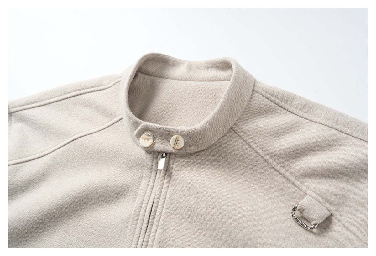 Close-up of the light beige jacket's stand collar, two buttons, zipper top, shoulder seams, and metal tab.
