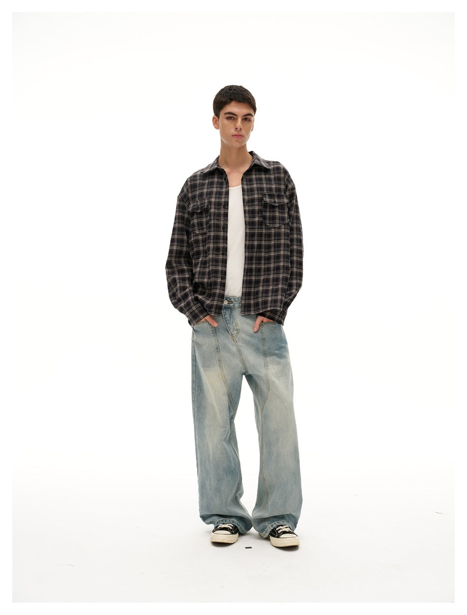 Front view of a model wearing a charcoal plaid button-up shirt with two chest pockets and loose light-wash jeans.
