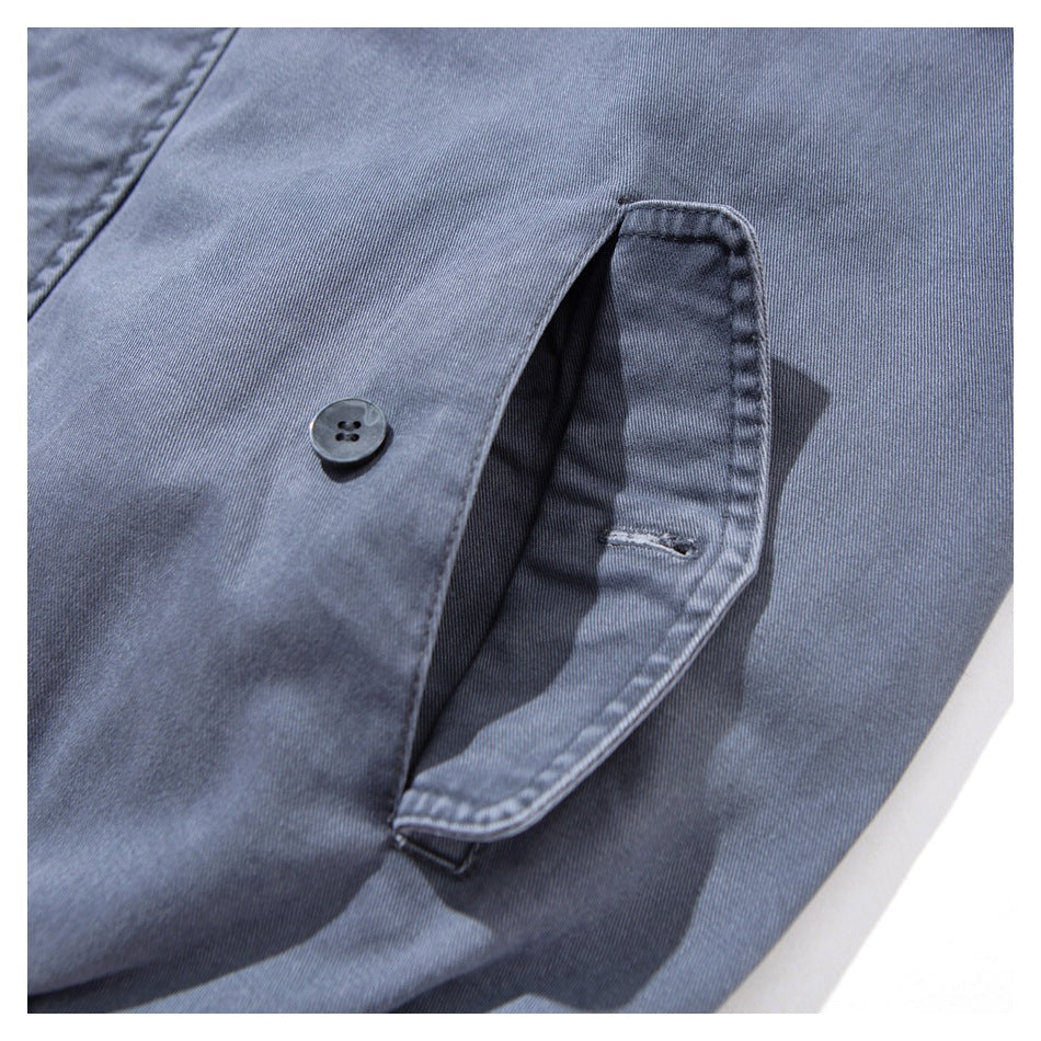 Close-up of a buttoned flap pocket on slate blue-gray jacket fabric.