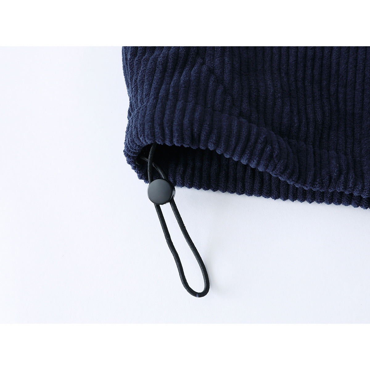 Close-up of the navy ribbed jacket's hem drawcord and round adjuster.
