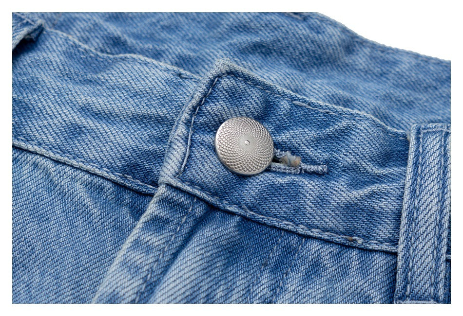Close-up of the metal waist button, buttonhole, belt loop, and denim stitching on light blue jeans.