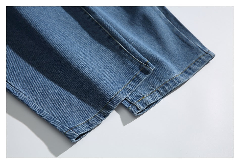 Close-up of the straight leg hems of blue faded jeans laid flat.