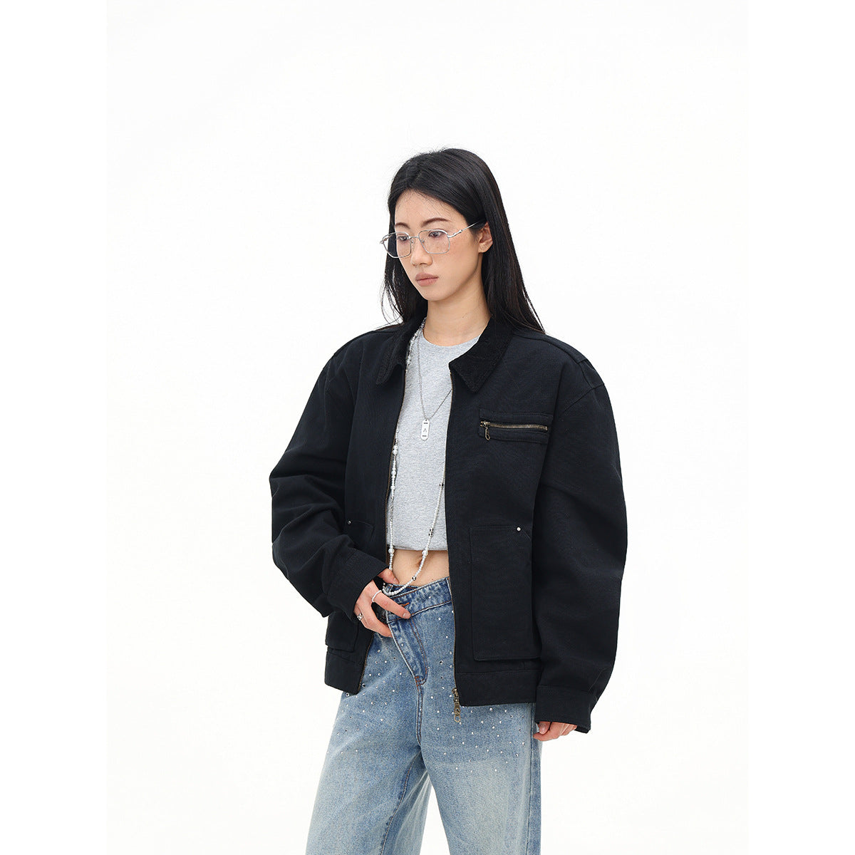 Three-quarter view of a model wearing an open black oversized jacket with a zip chest pocket and large front pockets.