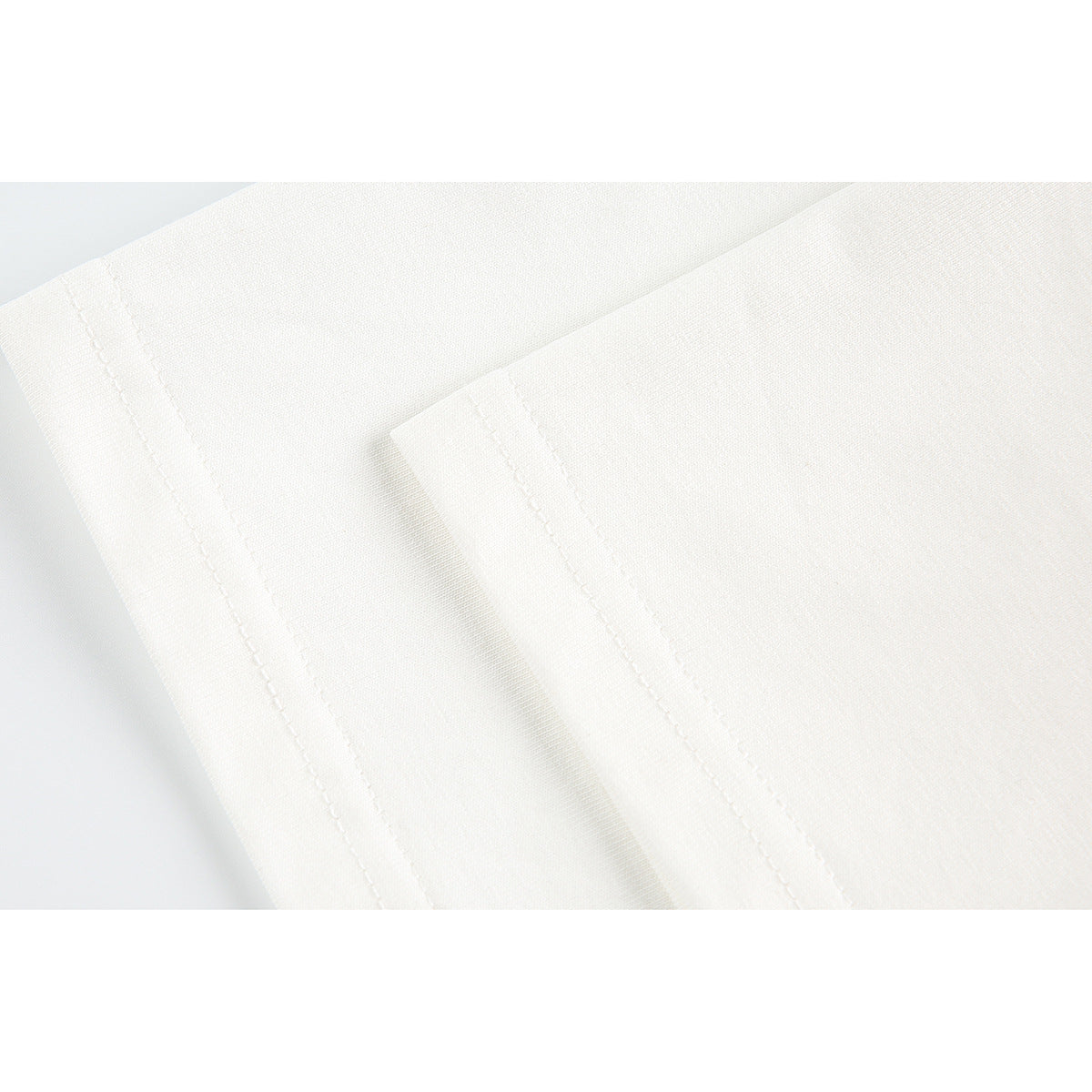 Close-up of stitched seams on off-white T-shirt fabric.