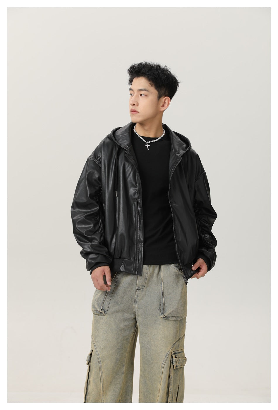 Model wearing an open black hooded jacket over a black shirt with loose faded cargo jeans.