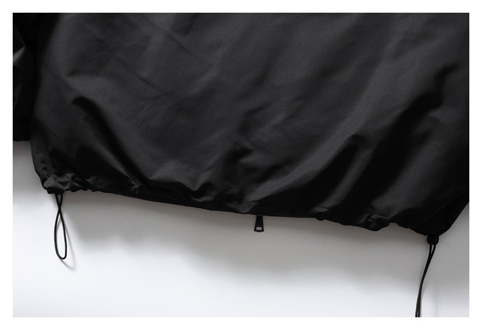 Close-up of a black jacket hem with adjustable drawcords and a center tab.