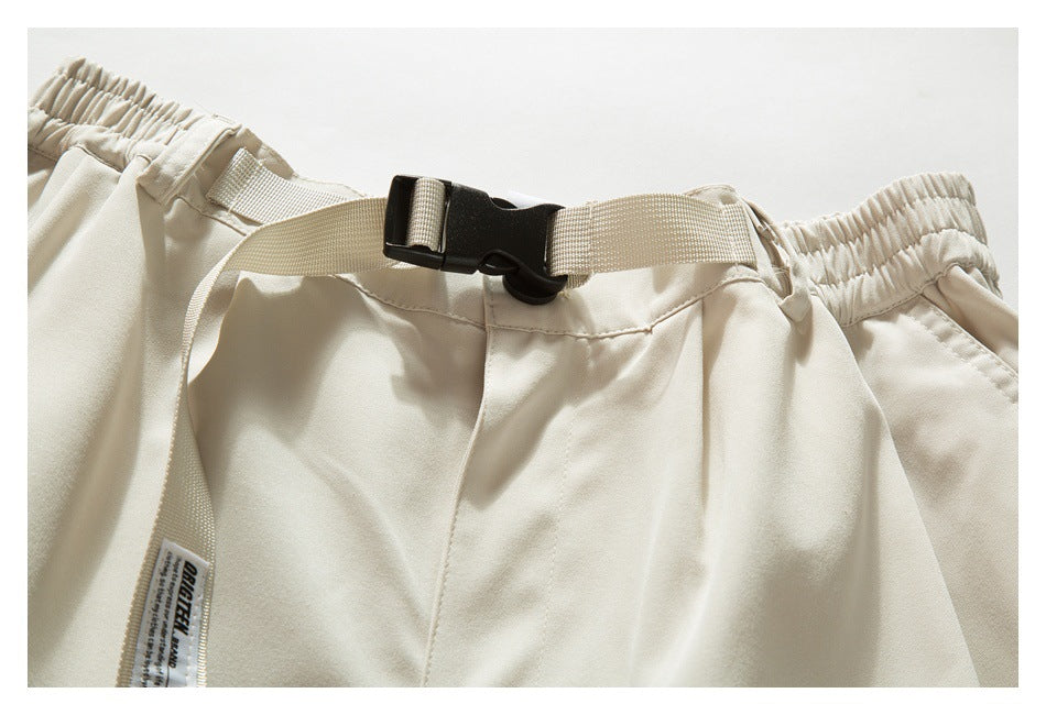 Close-up of the beige shorts' elastic waistband and adjustable webbing belt with a black buckle.
