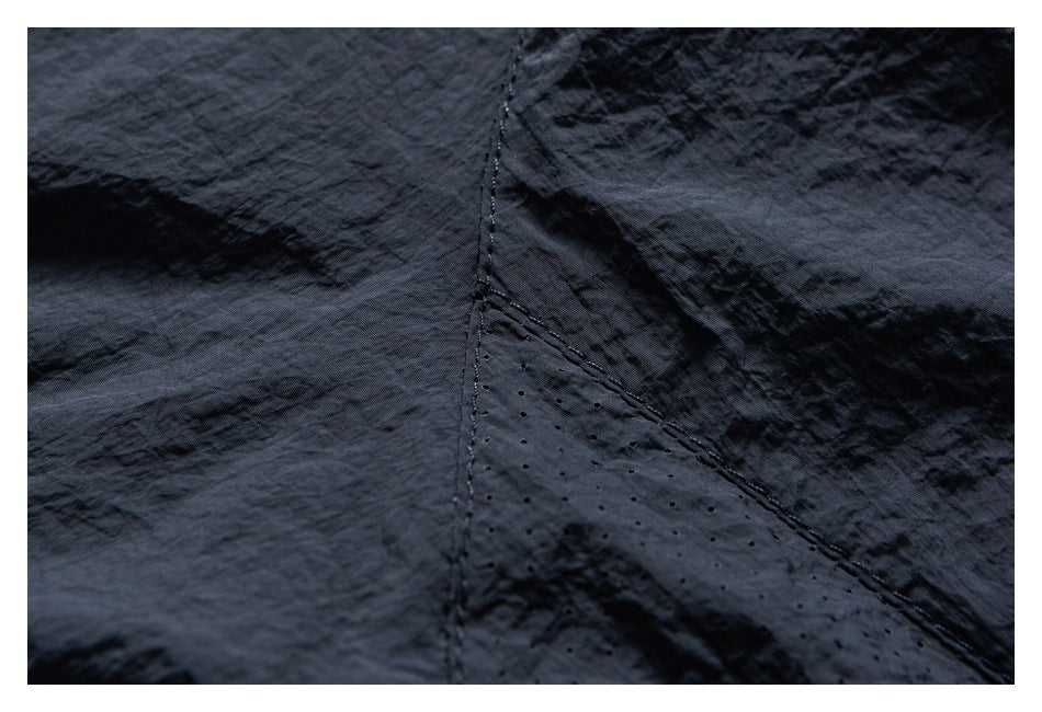 Close-up of a stitched seam and small perforations in dark garment fabric.