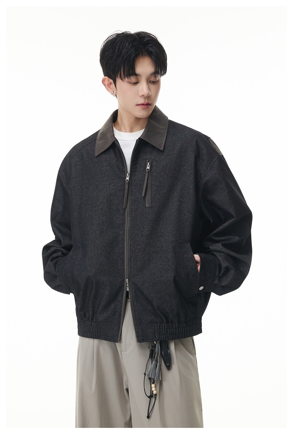 Model wearing a charcoal zip-front jacket with a contrasting dark collar, chest zipper pocket and gathered hem.
