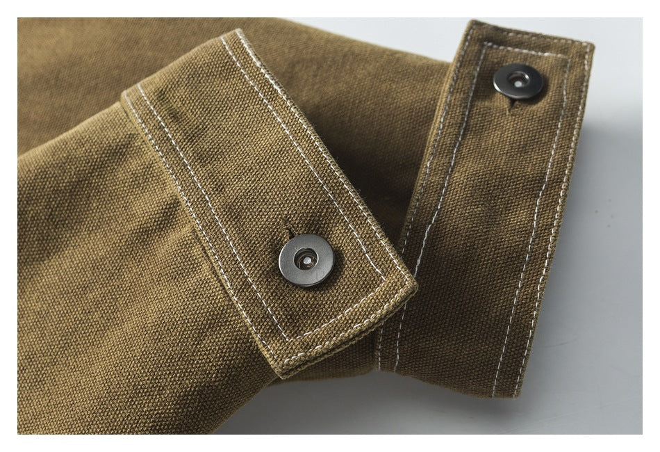 Close-up of two brown jacket tabs with metal snaps and contrasting stitching.