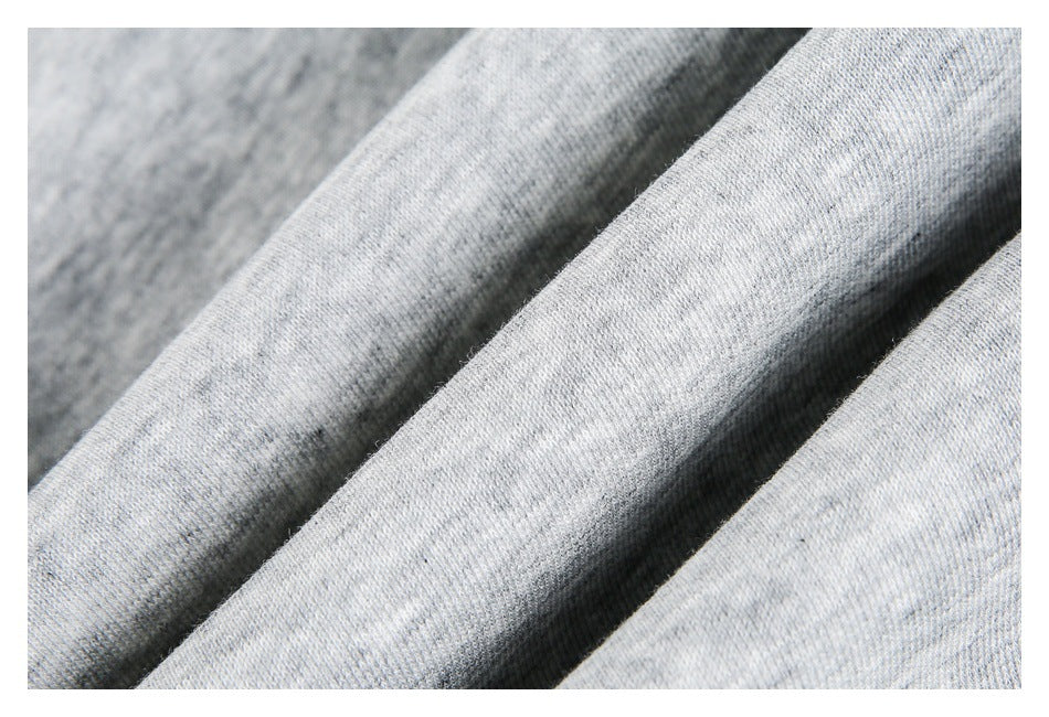 Macro view of the knit texture of light gray heather fabric folded into soft ridges.