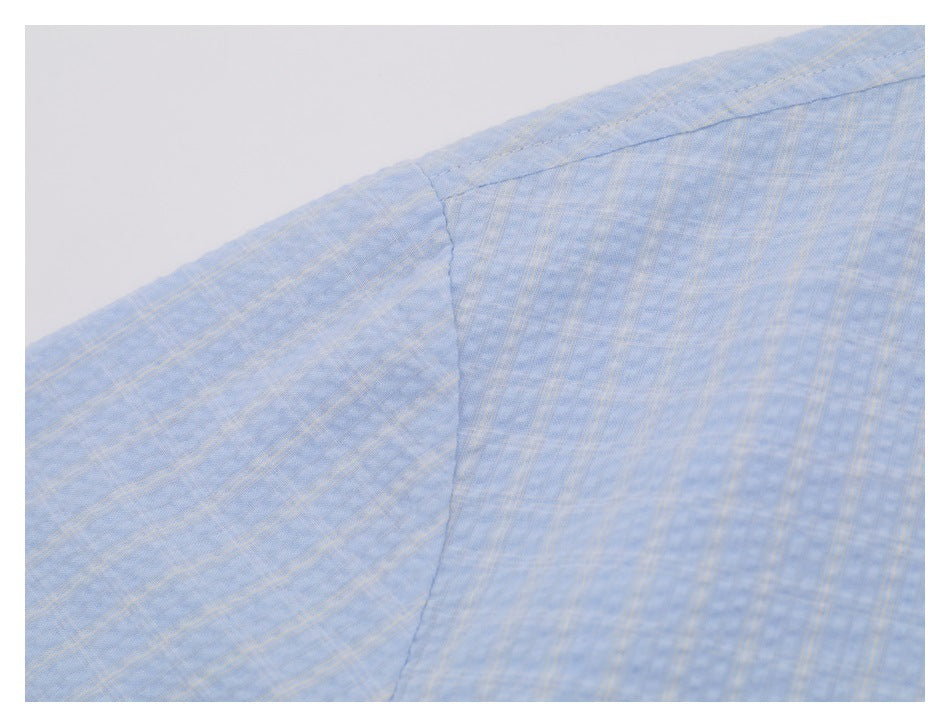 Close-up of a light blue shirt shoulder and sleeve seam with a subtle plaid pattern.