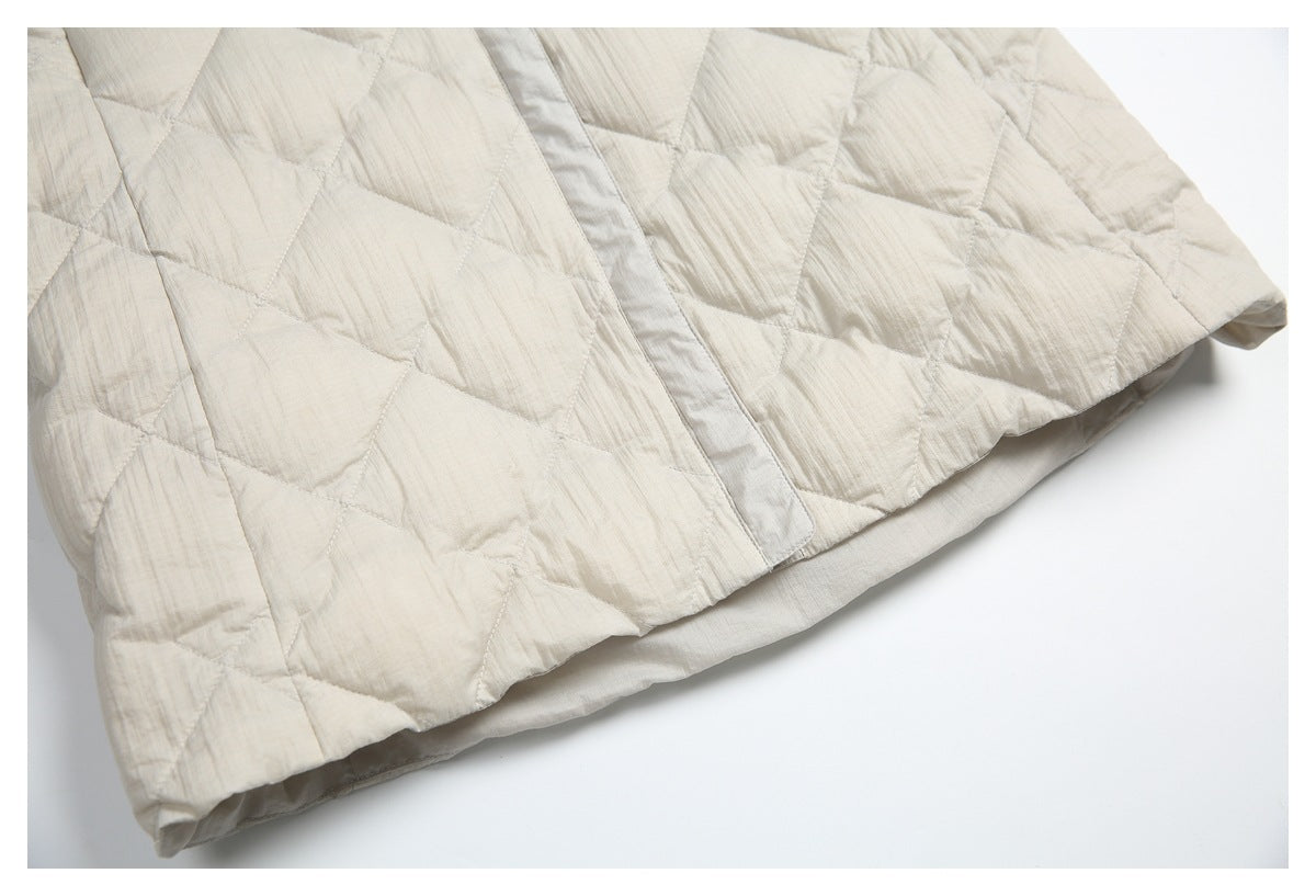 Close-up of the cream quilted jacket's lower front and curved hem.