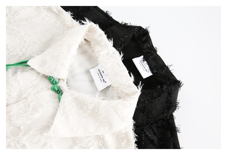 Close-up of ivory and black shirt collars, showing the textured fabric and sewn-in neck labels.