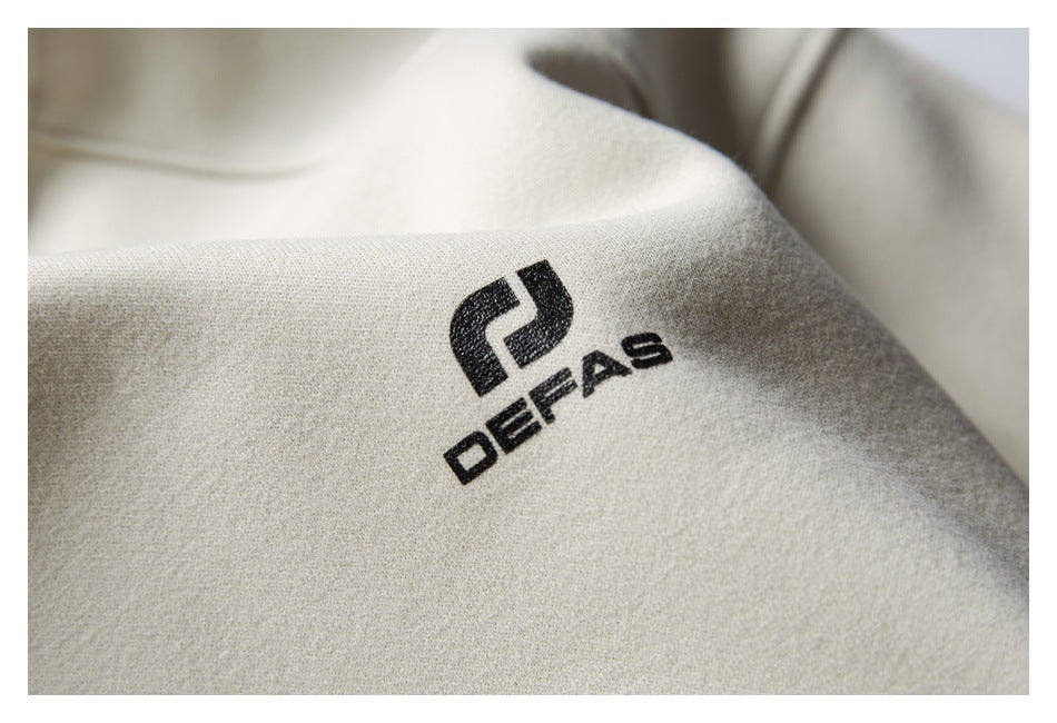 Close-up of a black DEFAS logo printed on cream sweatshirt fabric.