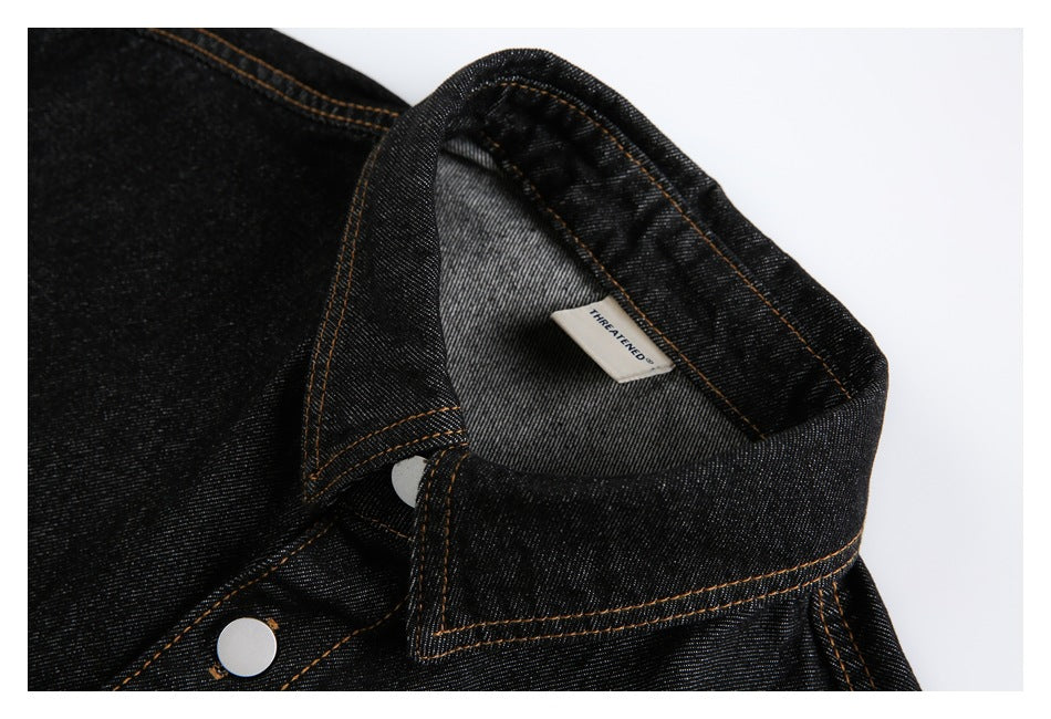 Black denim shirt collar and upper placket detail with a visible inner label and silver snap.