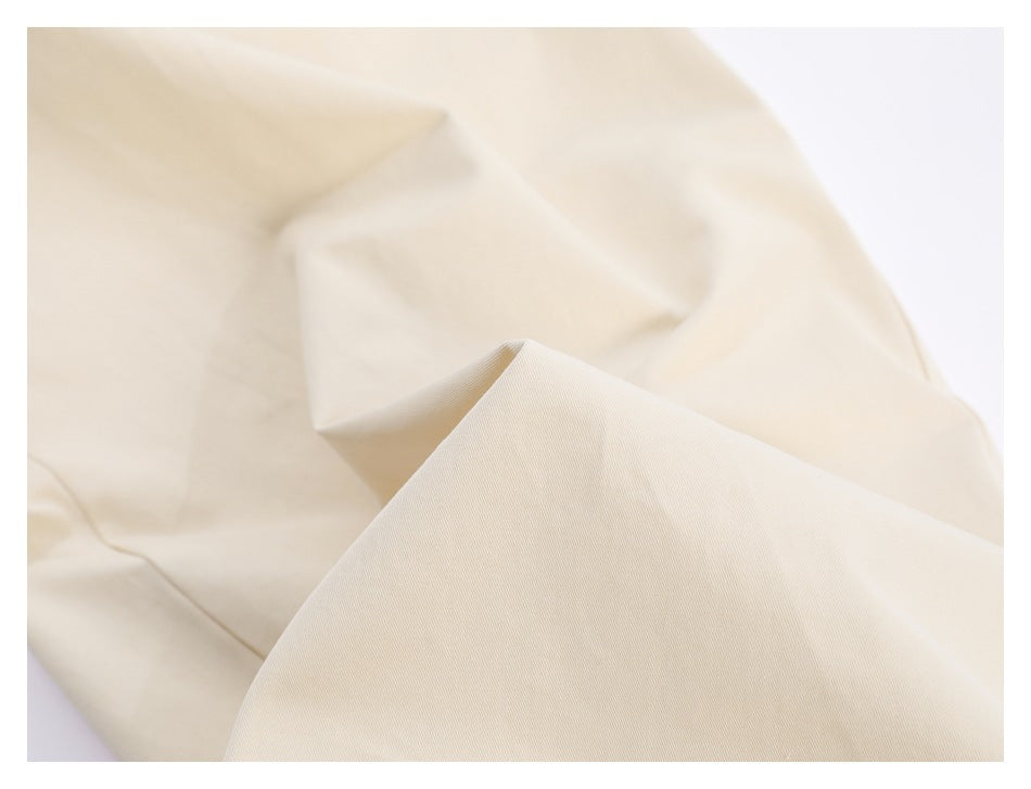 Close-up of cream trouser fabric draped in soft folds.
